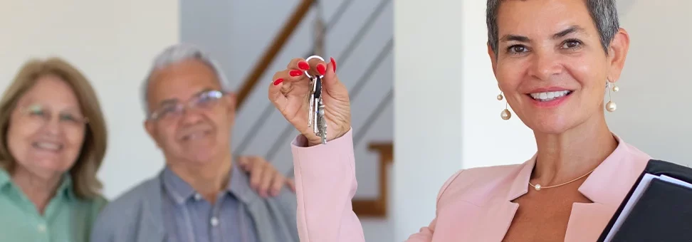 A businesswoman giving keys to elderly couple for apartment rent