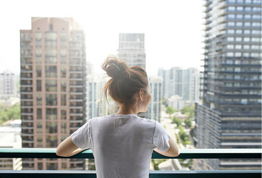 a girl looking at the other buildings from her balcony